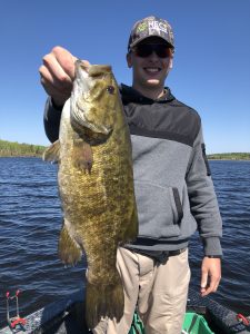 man holding large smallmouth bass in boat