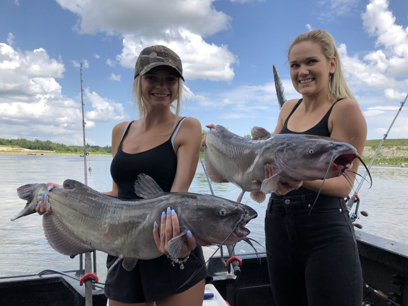 2 young ladies catching catfish from a boat